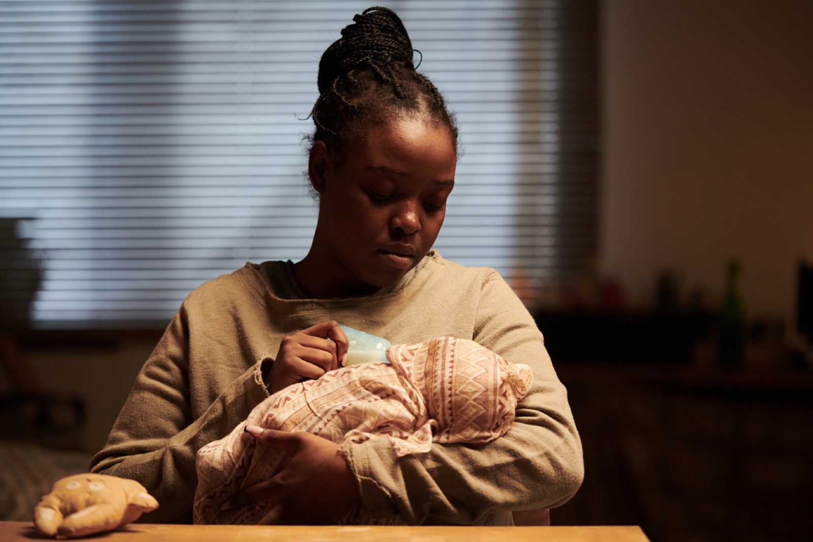 A mother feeding her baby alone in dim light late at night