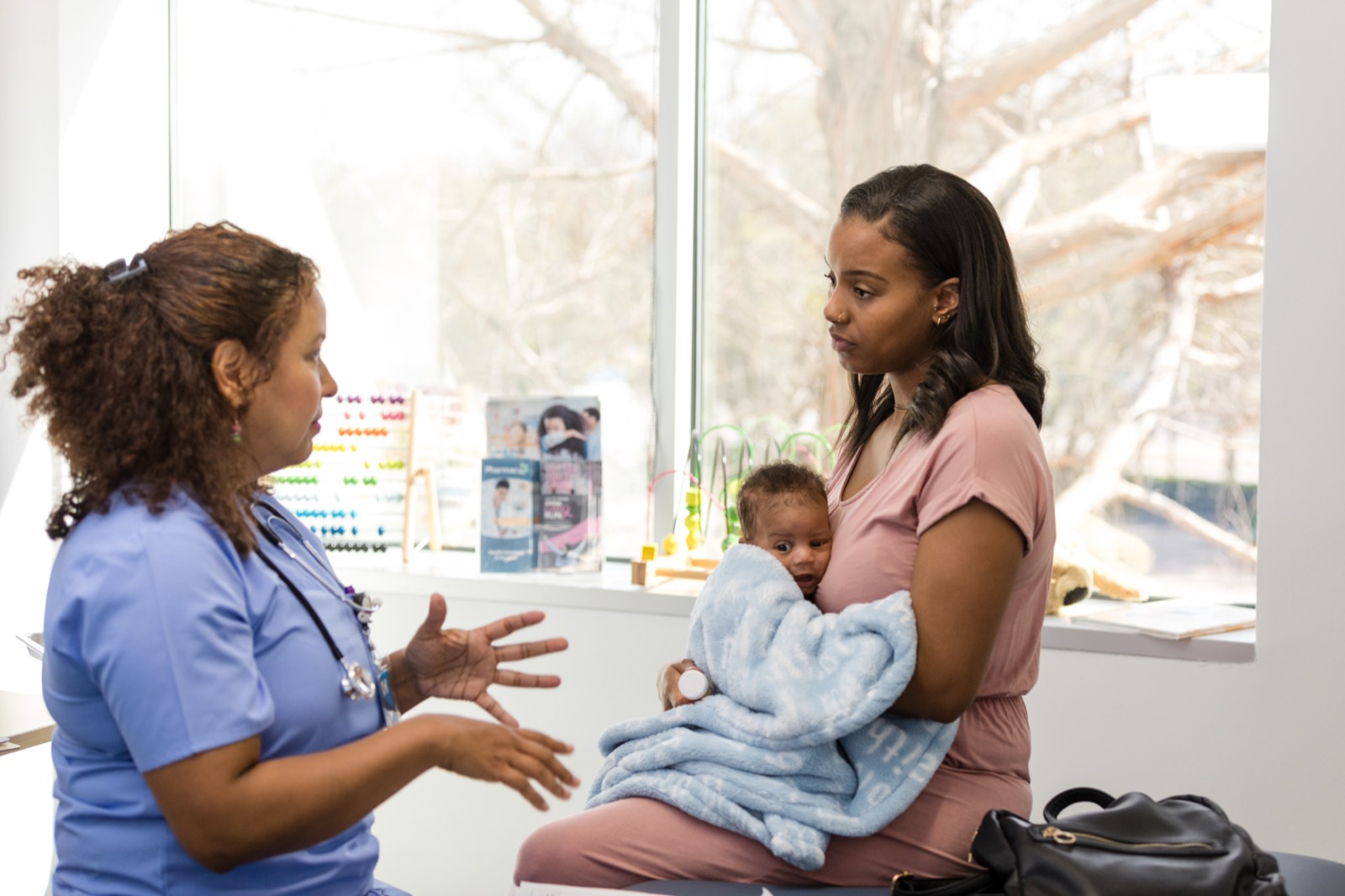 A nurse talking with a mother holding her baby at a clinic visit